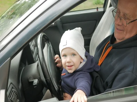 Grandfather plays with the boy in the car while driving. The grandson is very Stock Footage