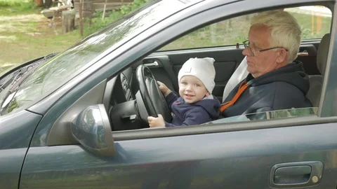 Grandfather plays with the boy in the car while driving. The grandson is very Stock Footage