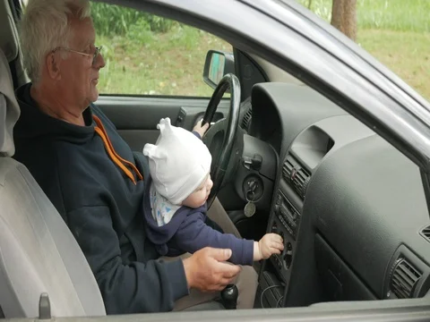 Grandfather plays with the boy in the car while driving. The grandson is very Stock Footage 76976745