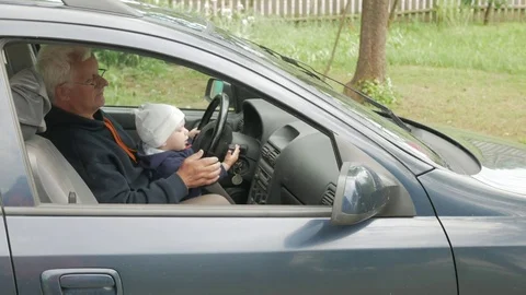 Grandfather plays with the boy in the car while driving. The grandson is very Stock Footage 76976874