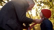 Grandfather Tying Granddaughters Scarf On Autumn Walk Stock Footage