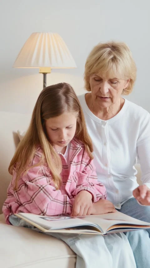 Grandma gesturing while reading book with girl Stock Footage 313048931