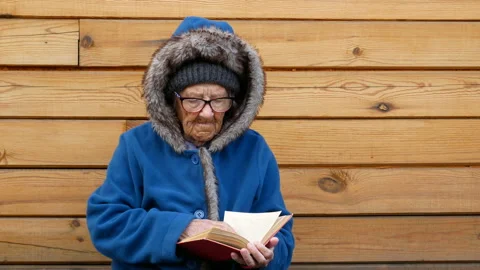 Grandma is reading and leafing through a book. Stock Footage 122379591