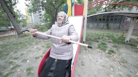 Grandma is riding on a children's hill. Stock Footage