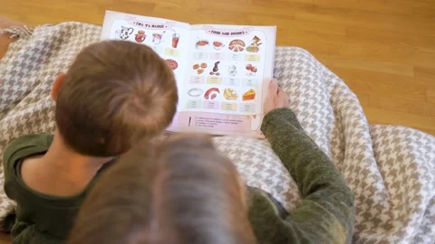 Grandma tutor reading textbook and talking to grandson a private lesson at home Stock Footage 232926622