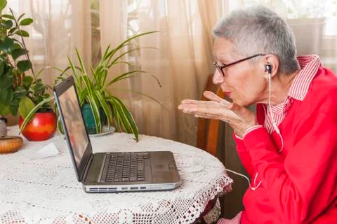 Grandma using laptop, camera and earphones for distant connections Stock Photos