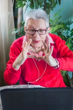 Grandma using laptop, camera and earphones for distant connections Stock Photos