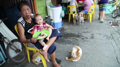 Grandmar feeding child and cat cleaning itself Manila Stock Footage
