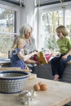 Grandmother and grandchildren (8-9) in the kitchen Stock Photos
