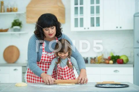 Grandmother and granddaughter cook pizza together, roll the dough with ...