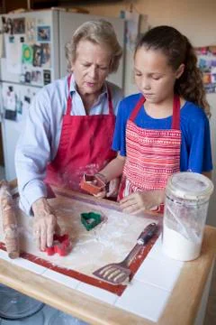 Grandmother and granddaughter cutting cookies from dough Stock Photos