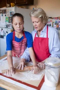 Grandmother and granddaughter rolling dough in kitchen Stock Photos