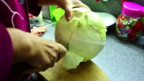Grandmother cutting cabbage with a sharp knife on a kitchen board. Video stock 292014642