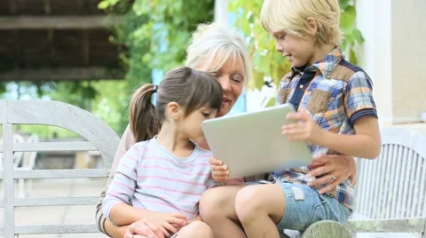 Grandmother with kids playing games on tablet Stock Footage