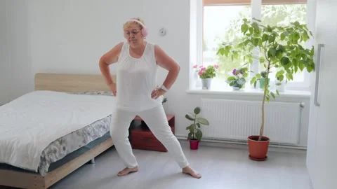 Grandmother practicing side stretch leg exercises during home workout fitness at Stock Footage 337909261