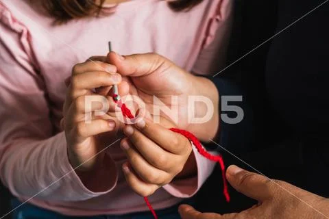 Grandmother teaches her little granddaughter how to sew. Stock Photos
