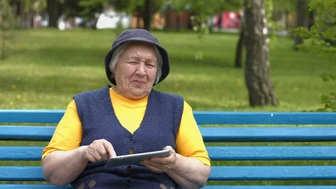 Grandmother uses a tablet computer. Видео 76092500