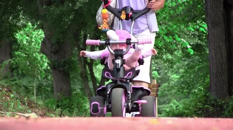 Grandmother walking her niece with a tricycle in park 01 Stock Footage 59588435