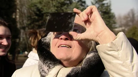 Grandmother, watching the solar eclipse through the dark glass Stock Footage 48217314