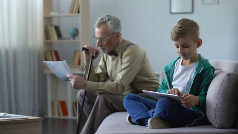 Grandpa reading press, boy using tablet, generations and technological progress Stock Footage 90008742