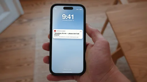 Grandparent scam message on a smartphone lock screen, elderly fraud prevention Stock Footage 346142584