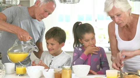 Grandparents With Grandchildren Making Breakfast In Kitchen Stock Footage