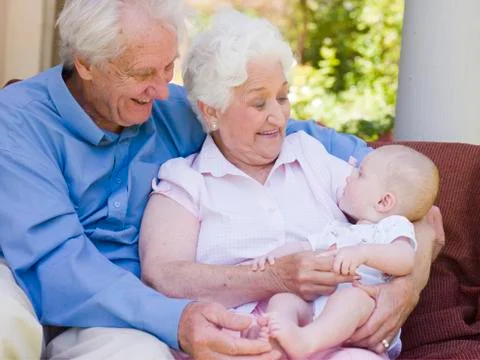 Grandparents outdoors on patio with baby smiling Stock Photos