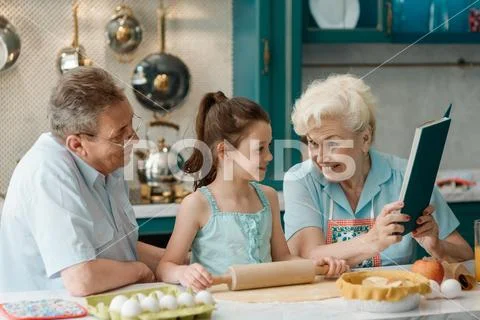 Grandparents teach granddaughter to bake. Warm atmosphere, happy family Stock Photos