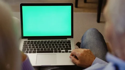 Grandparents using laptop computer with green screen while sitting on the sofa Stock Footage 82708054