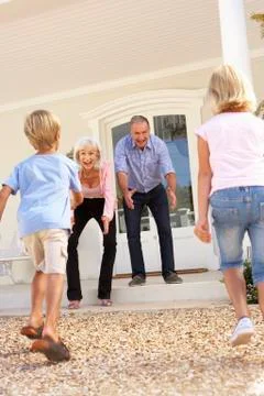Grandparents Welcoming Grandchildren On Visit To Home Stock Photos