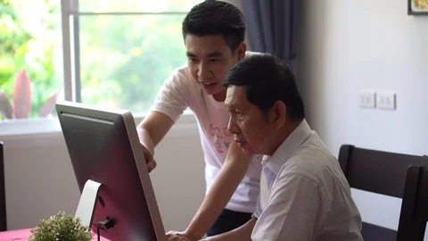 Grandson teaching grandfather how to Using computer and technology in home . Stock Footage 111032311