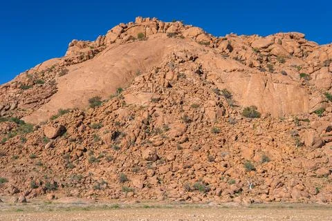 Granite boulder hill glows warm above dry grass in Namibia Stock Photos