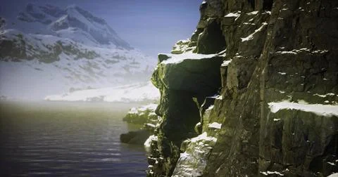 Granite cliffs rise over still water in a snow capped mountain landscape Ilustração Stock