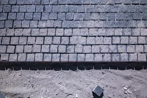 Granite cobblestone paving stones process on sand construction site Stock Photos