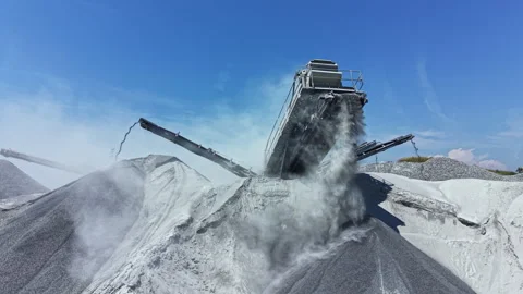 Granite quarry operates machinery to process stone material during midday under Stock Footage 337889823
