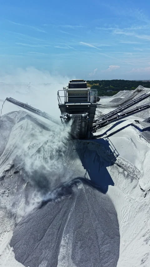 Granite quarry processing site with machinery moving rock dust under a blue sky Stock Footage 337906626