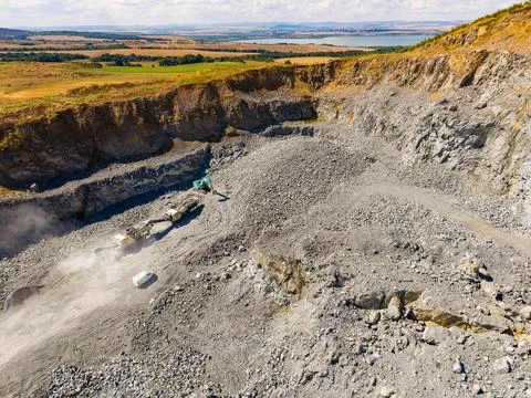 A granite quarry shows workers using machinery to extract stone from the grou Stock Photos