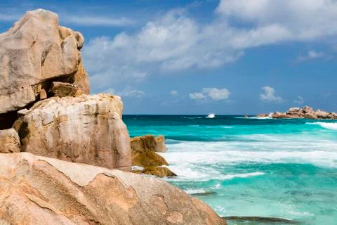 Granite rock formations in the foreground and background with turquoise water Stock Photos