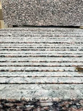 A granite slab displayed on vertically stacked granite slabs in a factory. Stock Photos