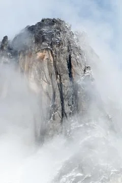 Granite spire surrounded by clouds Stock Photos