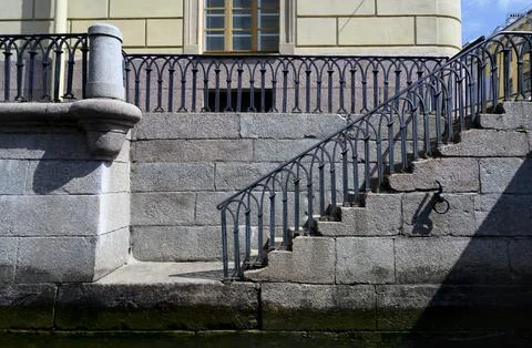 Granite steps with openwork railings of the 18th century leading to the river Stock Photos