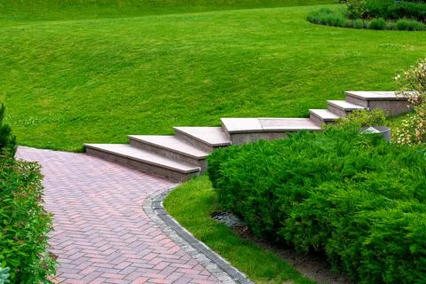 Granite steps to path from brick stone tile in a park on a slope. Stock Photos