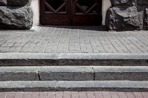 Granite steps on a pedestrian pavement made of stone tiles. Stock Photos