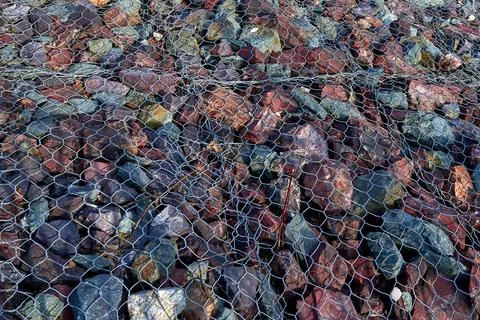 Granite stones under the grate. Pattern, background. Landslide protection. Stock Photos