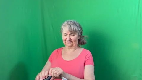 Granny against a green wall initially refuses, but then puts on a VR helmet Stock Footage 284324578