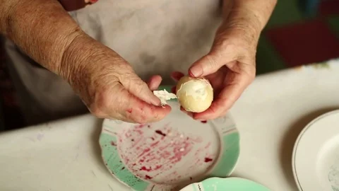 Granny cleans boiled egg. Preparation of a dish herring under a fur coat. Stock Footage 70269173