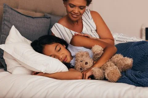 Granny looking at her granddaughter while she sleeping Stock Photos