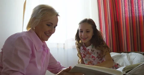 Granny sitting on couch next to her granddaughter and looking through photo Stock Footage 66286572