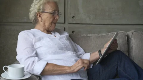 Granny working with digital tablet on couch Stock Footage 54653068