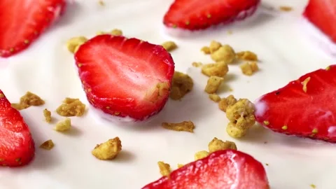 Granola falling down on white yoghurt with fresh red juicy strawberry pieces Stock Footage 246850337